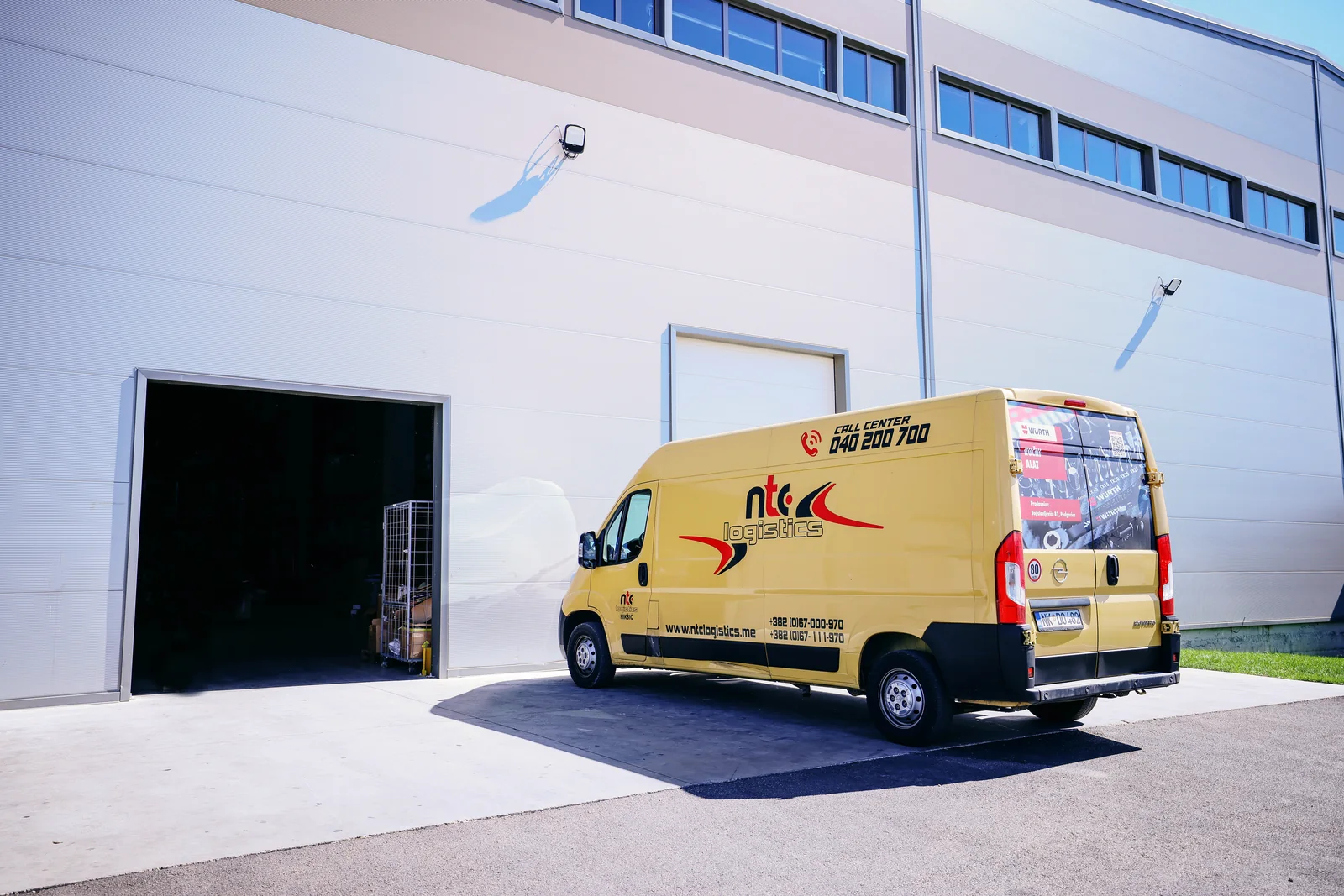 Žuto NTC Logistics dostavno vozilo ispred skladišnog ulaza